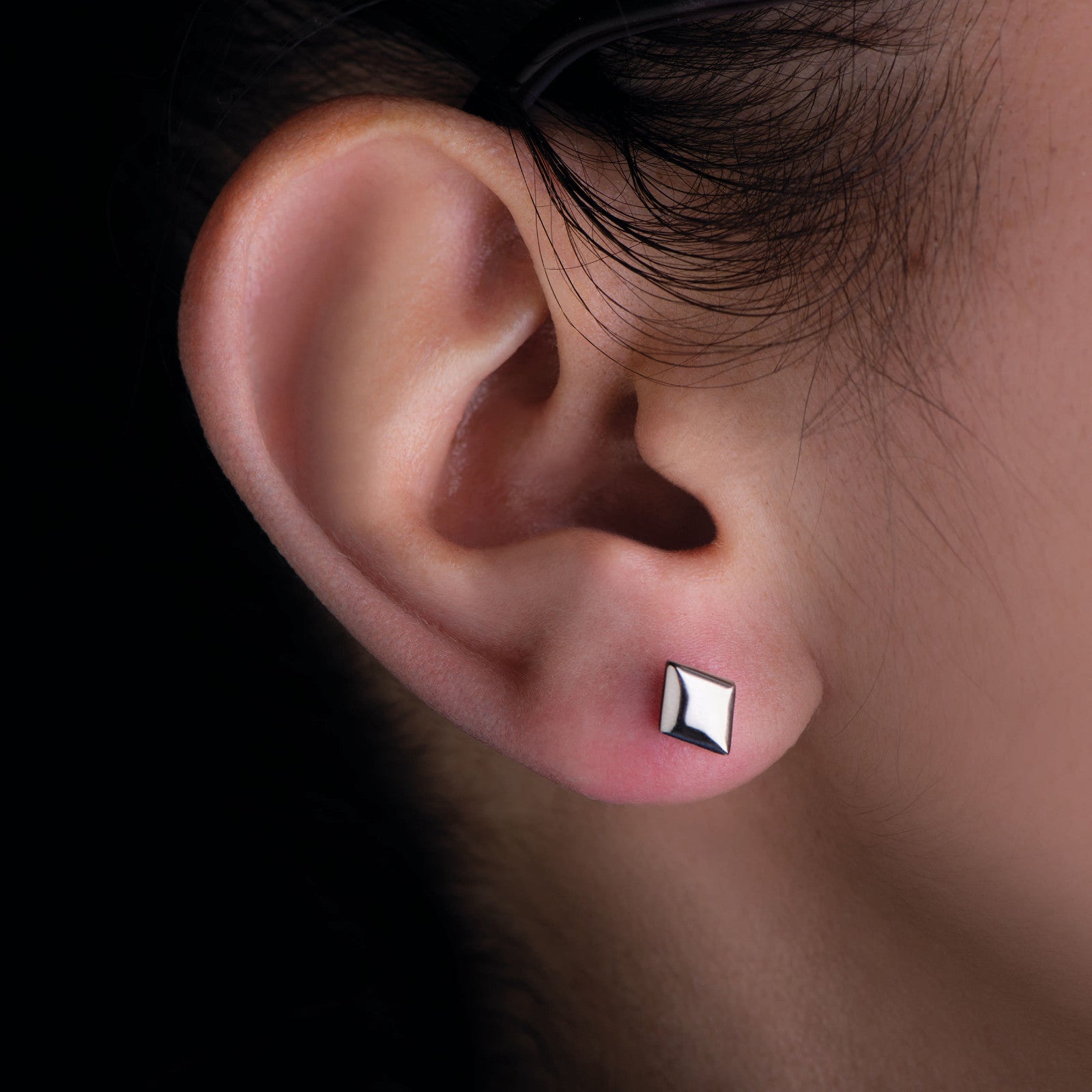 Polierter Titan Ohrstecker in Routenform am Ohr eines Models